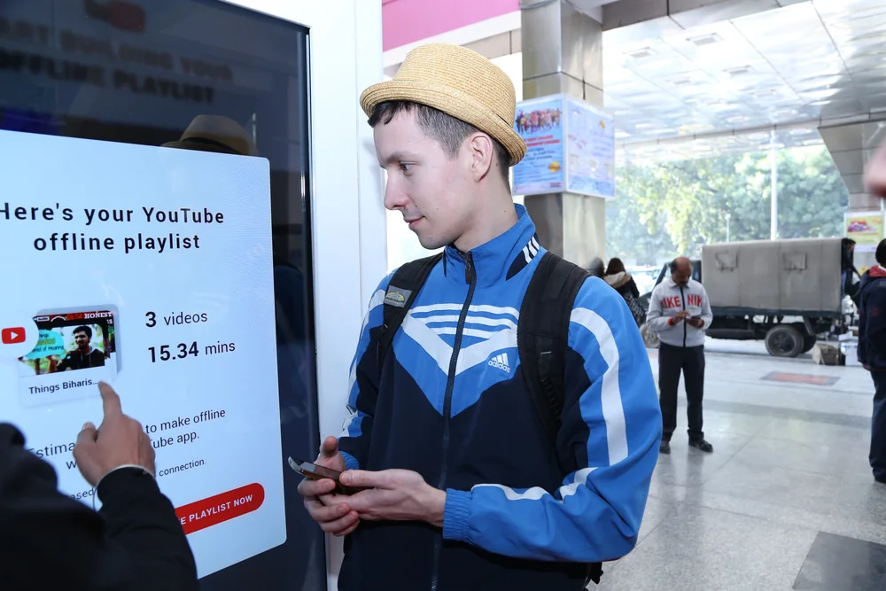 Two men at the kiosk browsing Bollywood titles and dragging a video into the playlist.