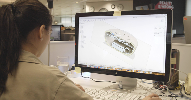 Designer modelling the round key housing in CAD on-screen, refining the compass-face proportions.