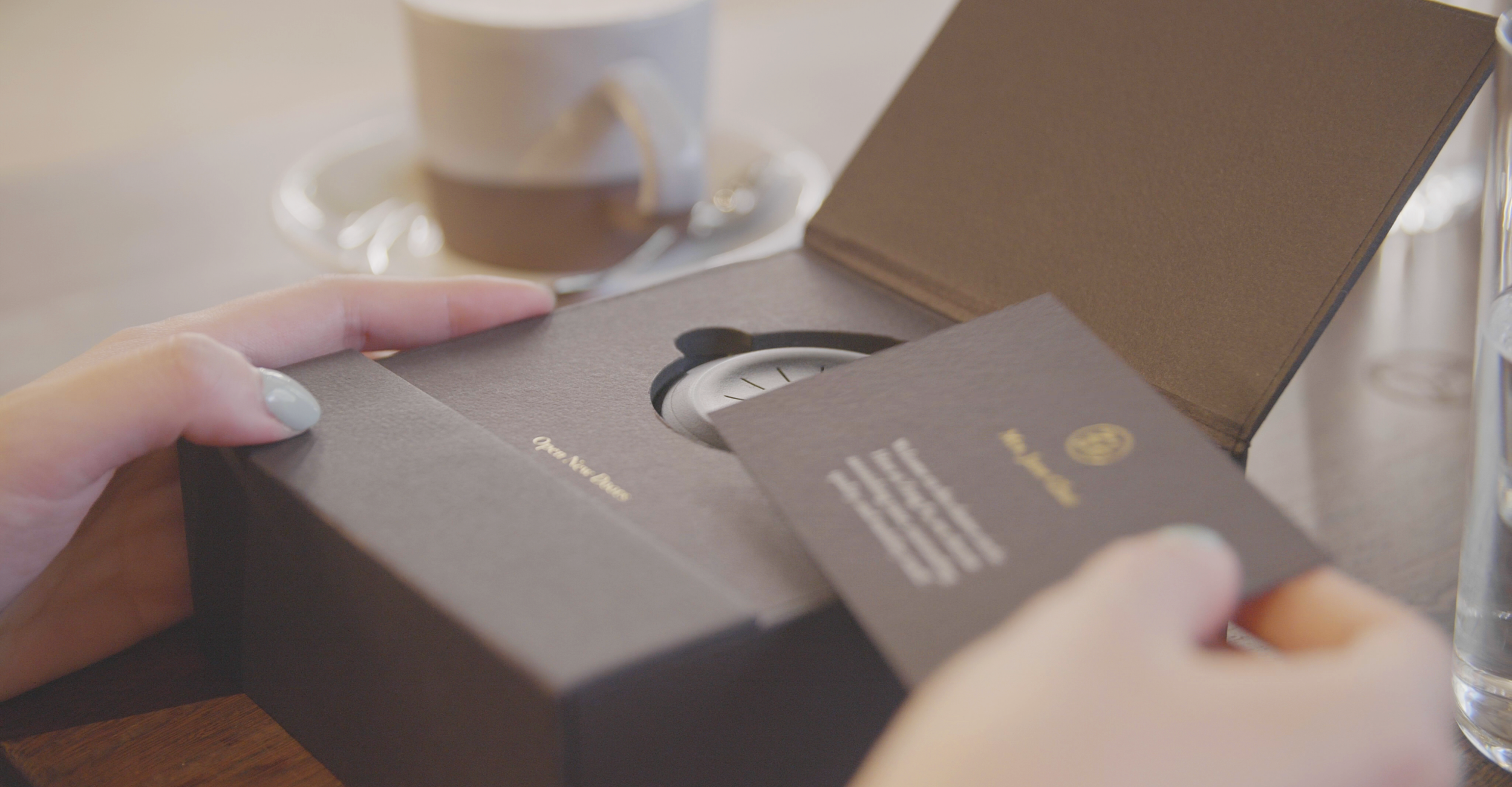 An owner lifting the welcome kit from the Open New Doors box, the smart key nested inside beside a coffee.